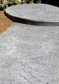 Custom stamped circular brick pattern grey in color and sealed walkway. 